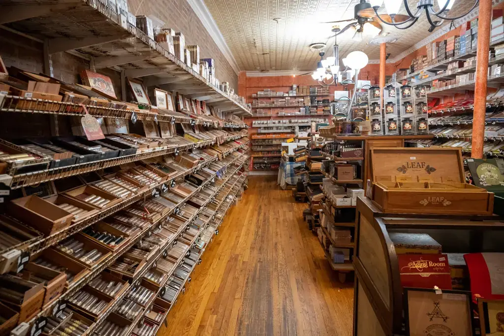 The walk in humidor aisle at Edward's, open cedar cigar boxes on stepped shelving under a pressed tin ceiling