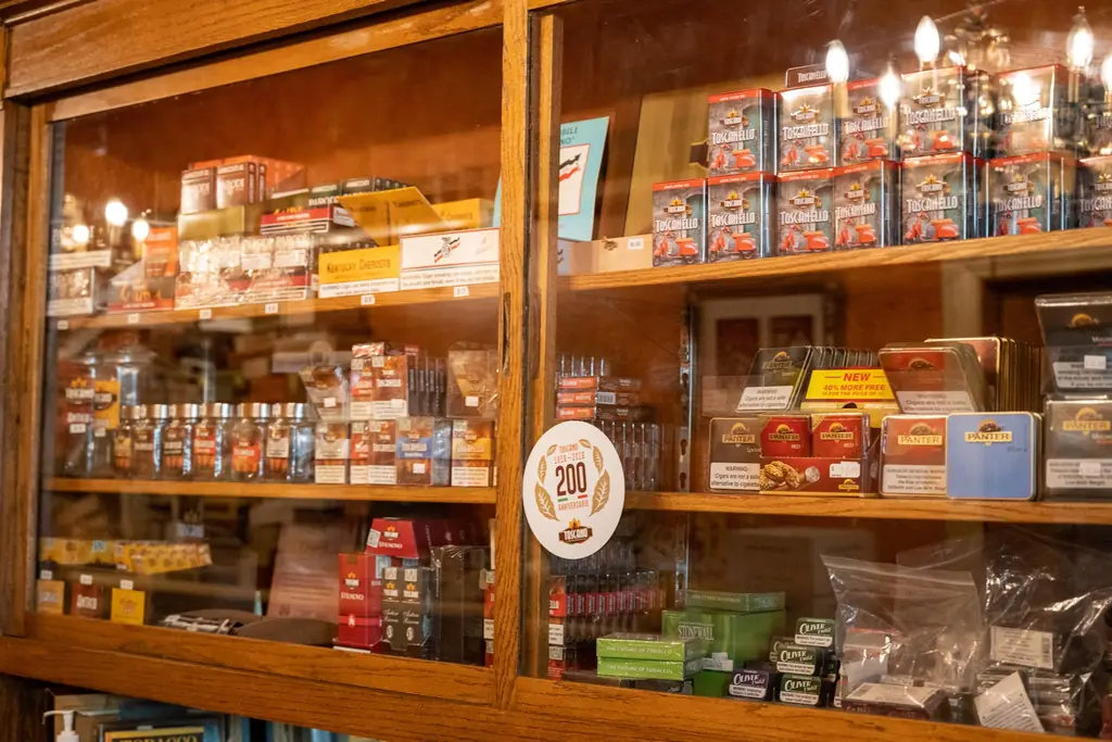 Oak display case of tinned and small cigars at Edward's, with legible Surgeon General warning labelling